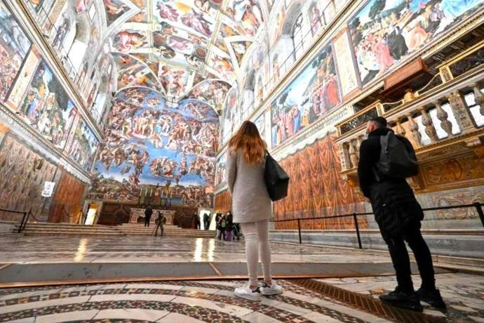 Dos mujeres turistas mirando el techo de la Capilla Sixtina